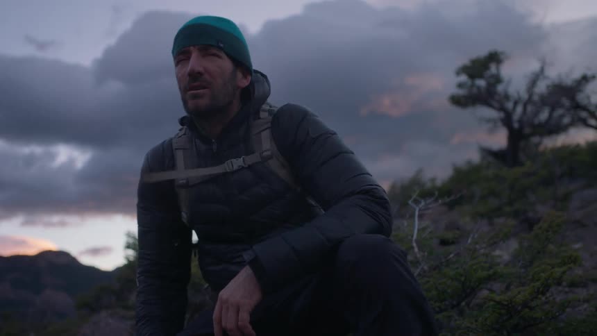 A hiker sits in the mountains at sunset