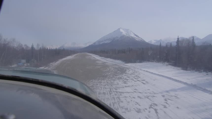 An airplane approaches a remote runway in the wilderness
