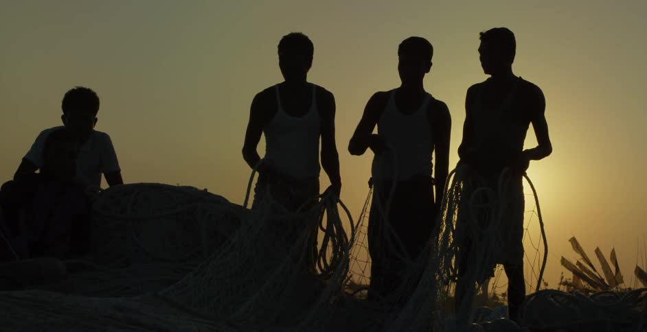 A group of people hold a net on a hill at dawn