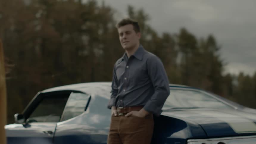 A man and woman stands outside next to a car