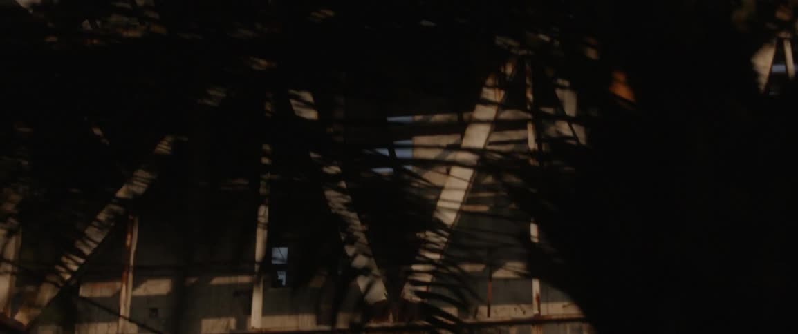 A vehicle passes beneath a city structure and trees