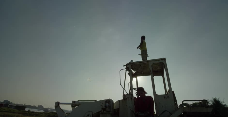 A man on a tractor flies a kite