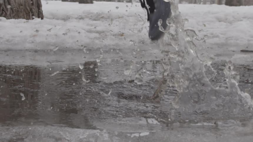 A person splashes through a slushy puddle