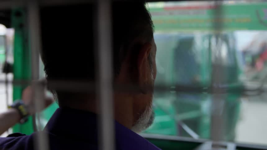 Man riding on a bus looks out at the city