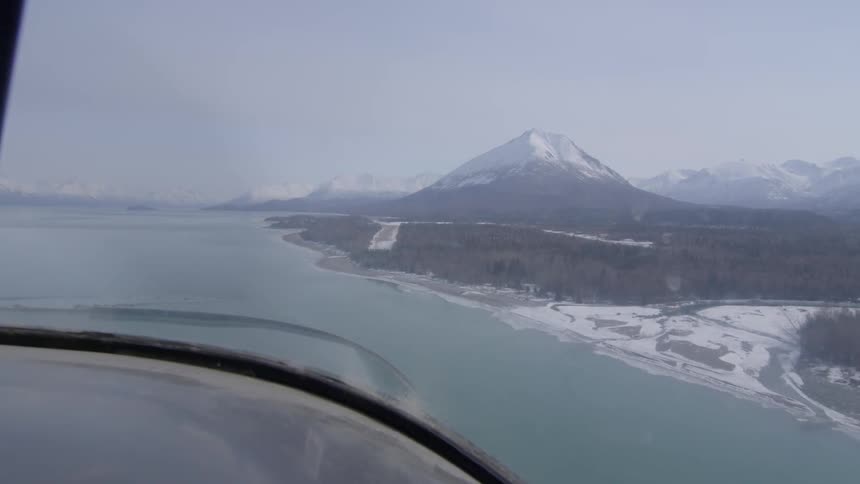 Aerial view of a lake, snowy beach and mountain range