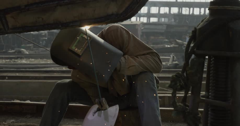 Sparks fly around a welder as he works outside