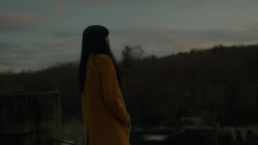 A woman in a yellow jacket is walking around with her hands in her pockets