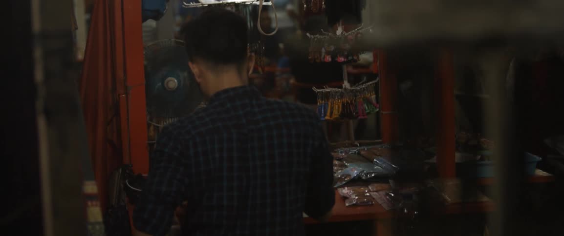 A man works in a workshop in front of a fan