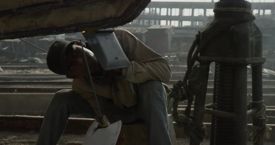 Man welding piece of metal in workshop during the day