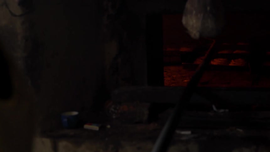 A blacksmith works in a kiln