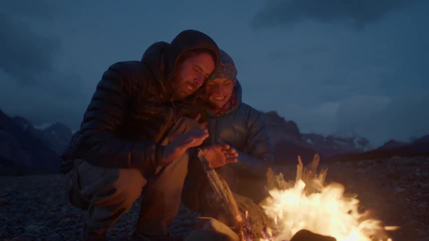 A couple sit together by the campfire