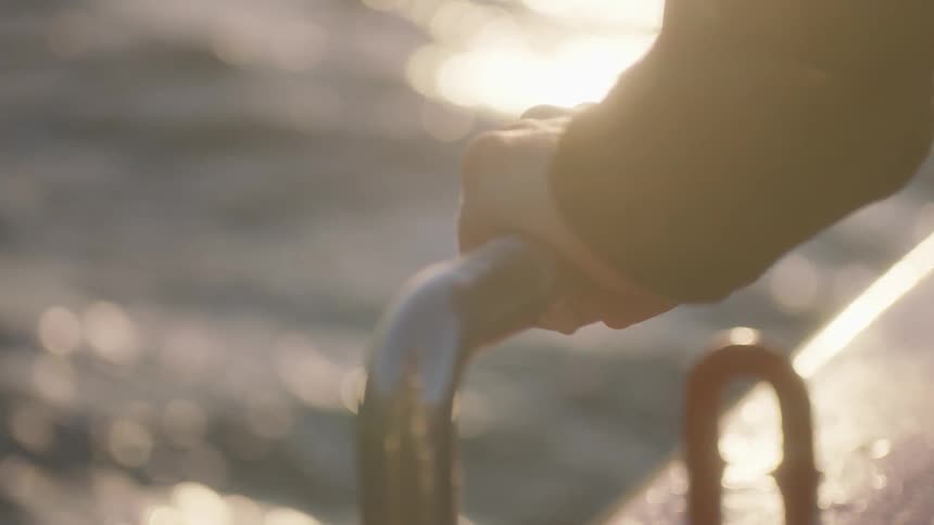 Person holding onto a railing leaning over water