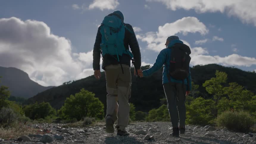 Two people hike outside holding hands