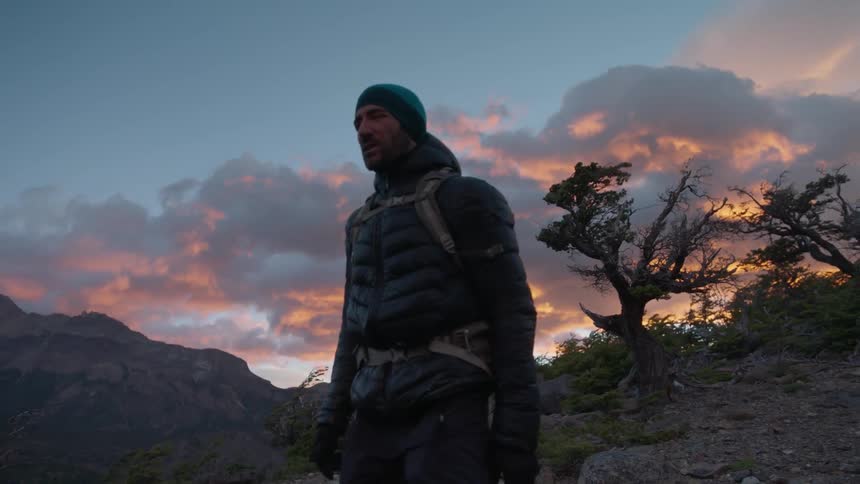 A man hikes in the mountains at sunset
