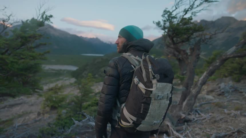A hiker carries a bag through the wind