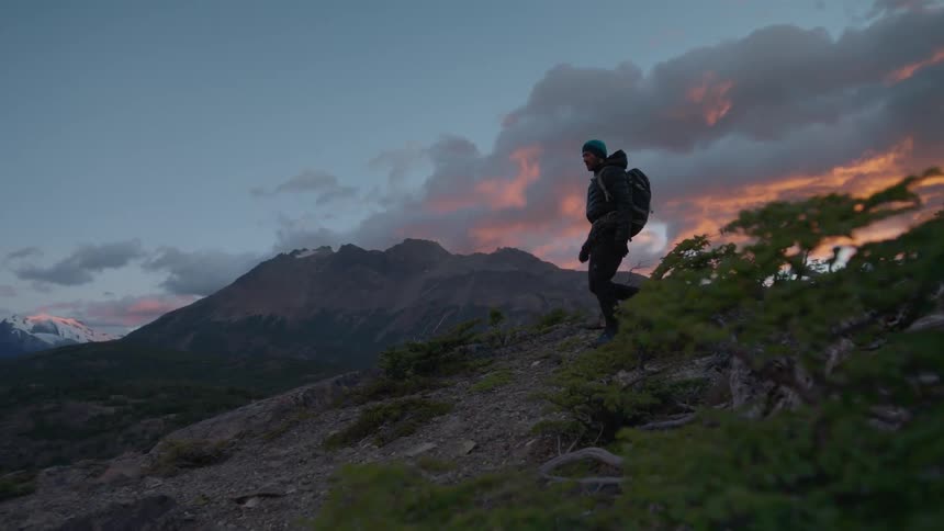 A man is hiking downhill on a windy day