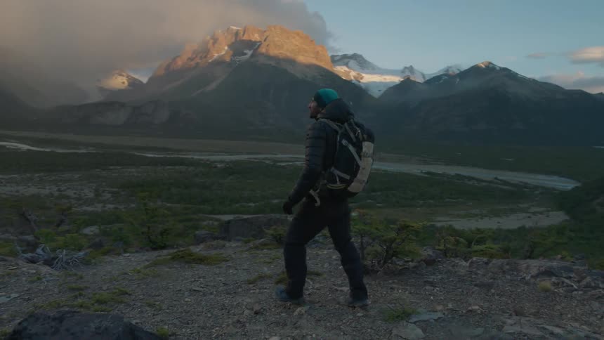 A hiker walks in the mountains at sunset