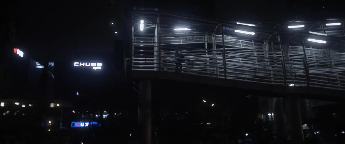 A person is walking at night on a covered pedestrian ramp in the city