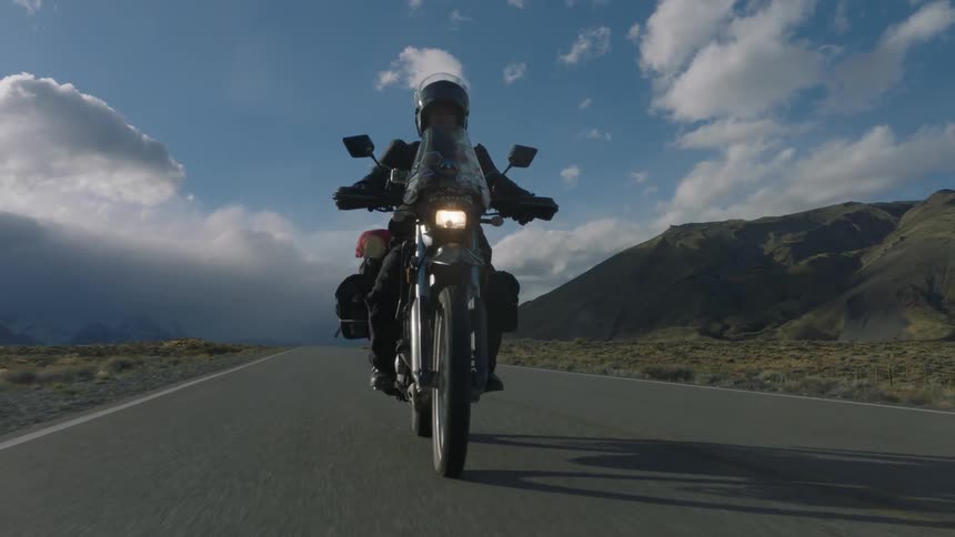 A person rides his motorcycle down the long road