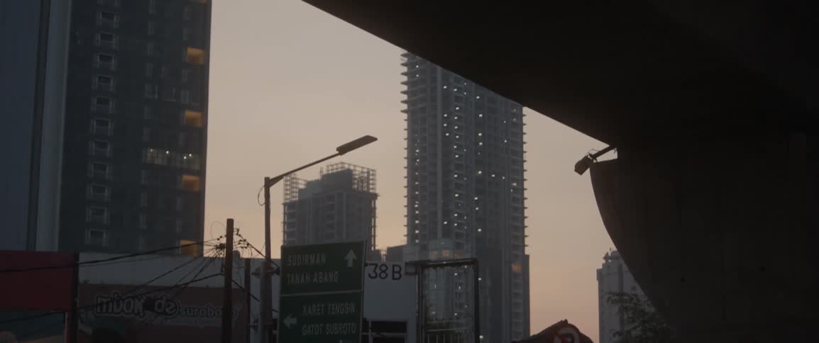 A tall building is ahead from under the overpass