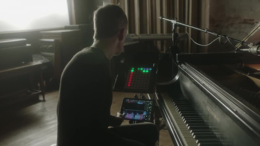 People are performing in a studio on drums and piano
