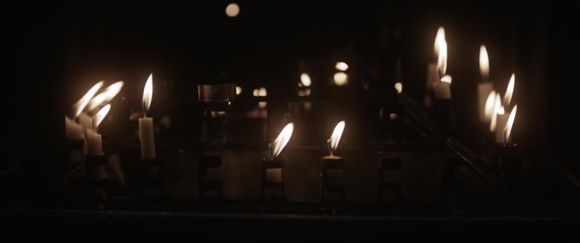 There are many lit candles in this dark room