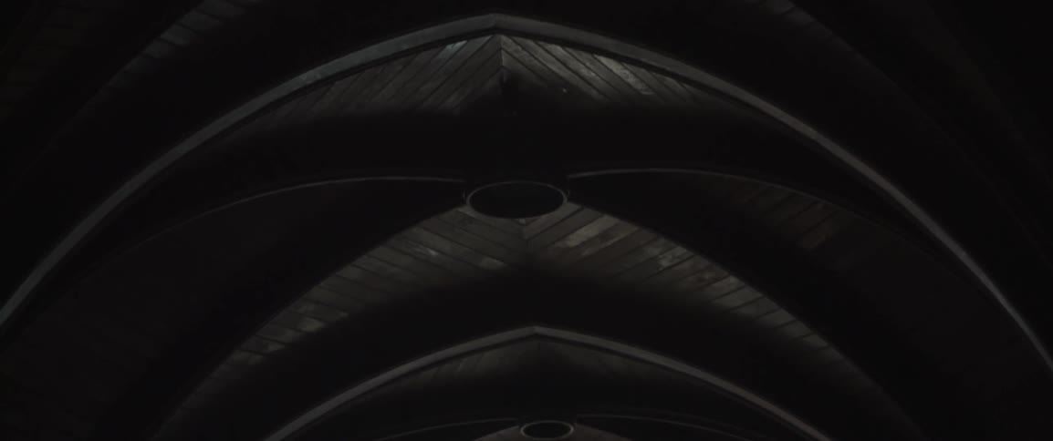 A wood domed ceiling curves towards stained glass windows