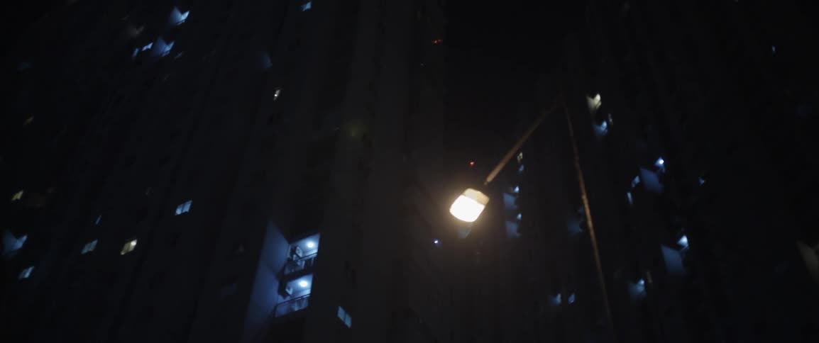 A street light shines down below a tall building at night