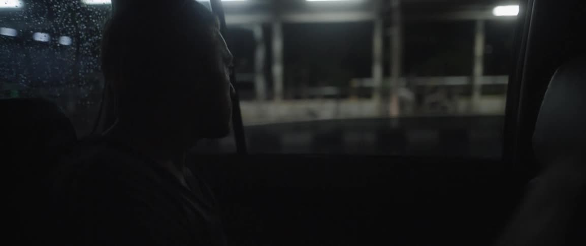 A man looks out the window of a moving vehicle at night