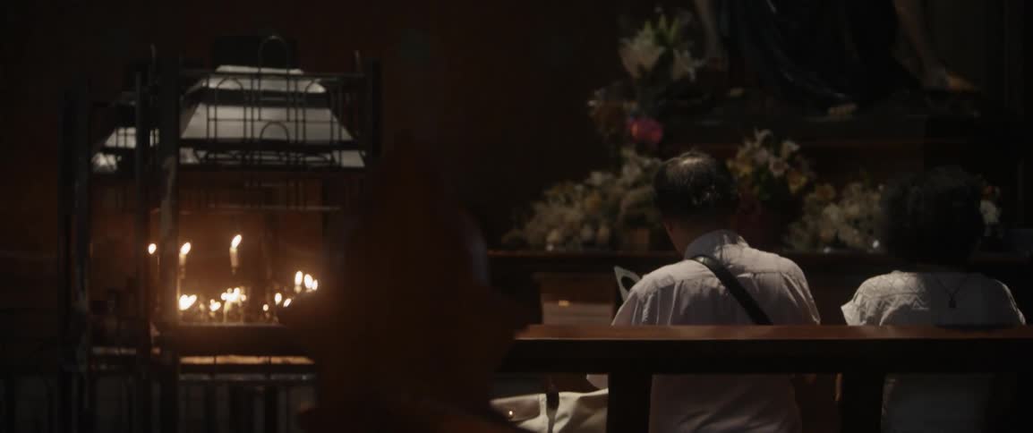 A man sits next to burning candles