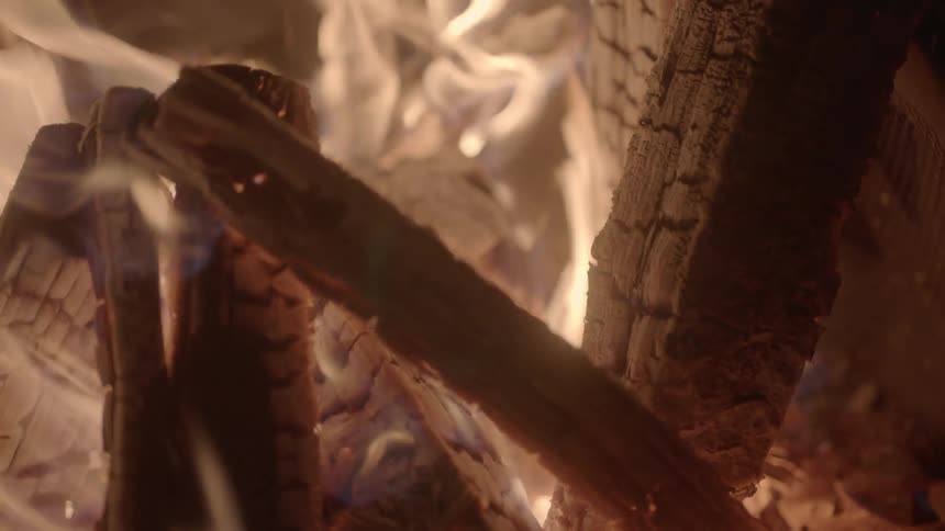 Wood burning and glowing hot in a campfire at night