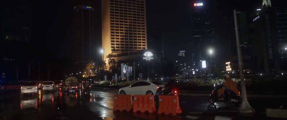 Vehicles travel down a busy city street at night