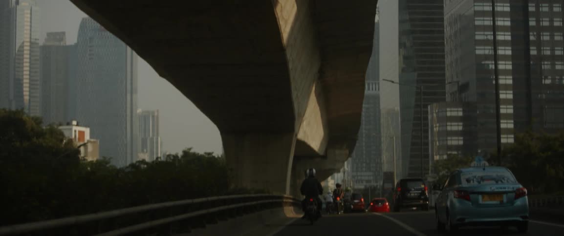 Motorbikes and cars travel down a busy road