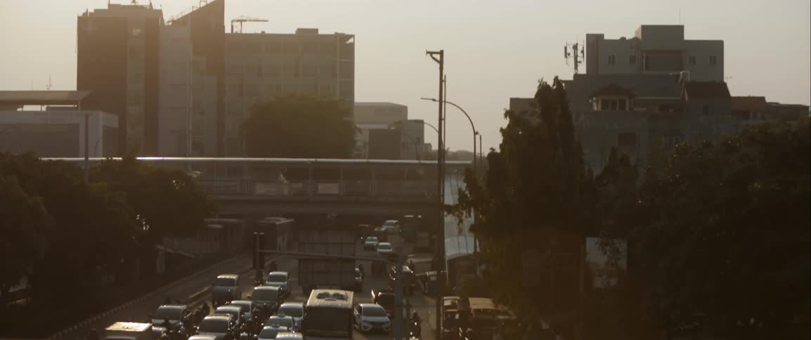 Cars drive on a city street at sunset