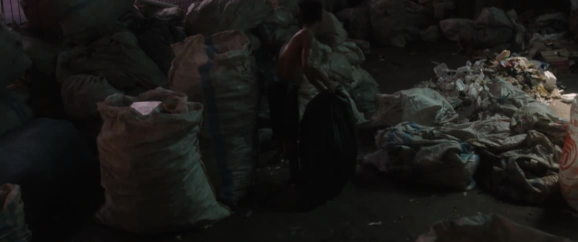 A man hauls a bag of trash in a dump