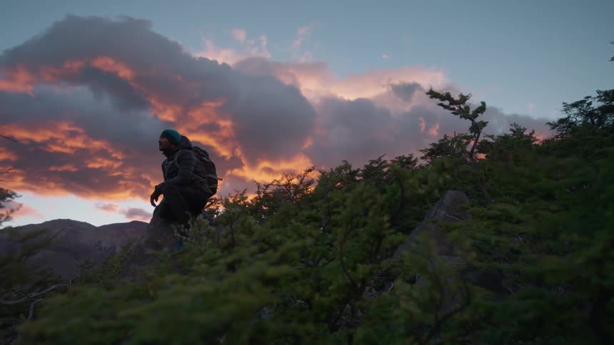 A man is hiking downhill in high winds