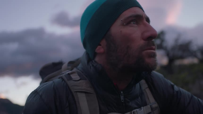 Man wearing a backpack in nature looks up