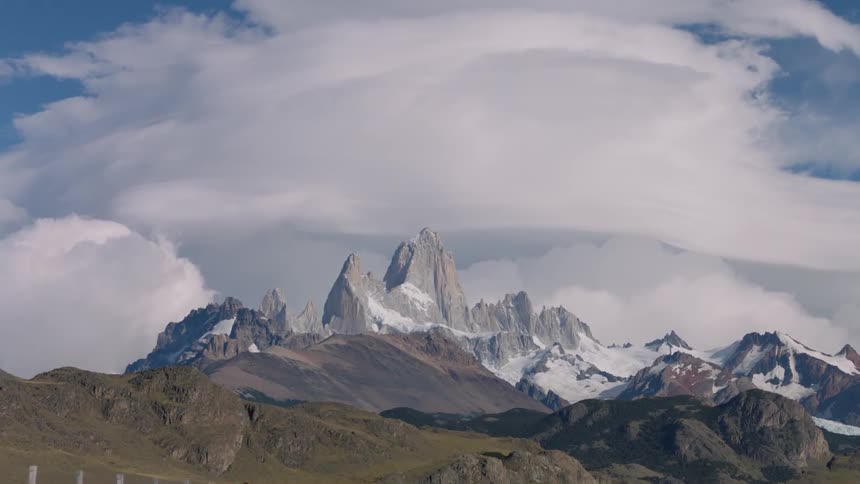Clouds loom above mountaintops with a green valley below