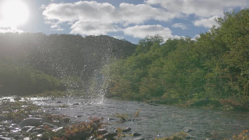 People stand near a stream skipping rocks
