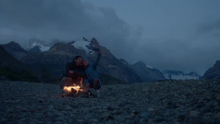 People sitting next to a campfire on a cloudy night