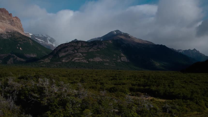 Clouds hang above a field and mountains