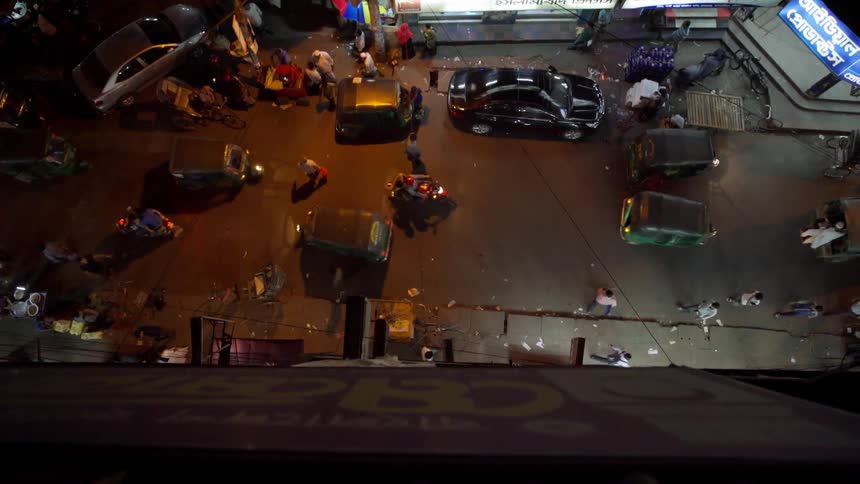 Pedestrians and vehicles commute through a city at night