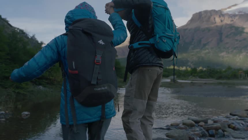 A man helps a woman cross a stream
