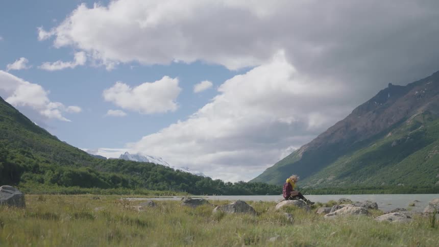 A person is sitting on the rocks by the lake ahead