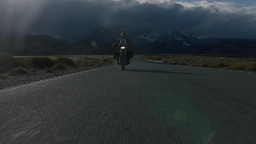 The road is empty with only one motorcycle driving