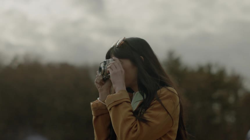 A woman picks up her camera to take a photograph