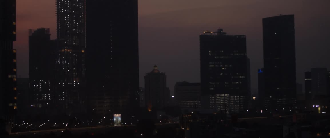 A large city with many tall buildings light up at sunset