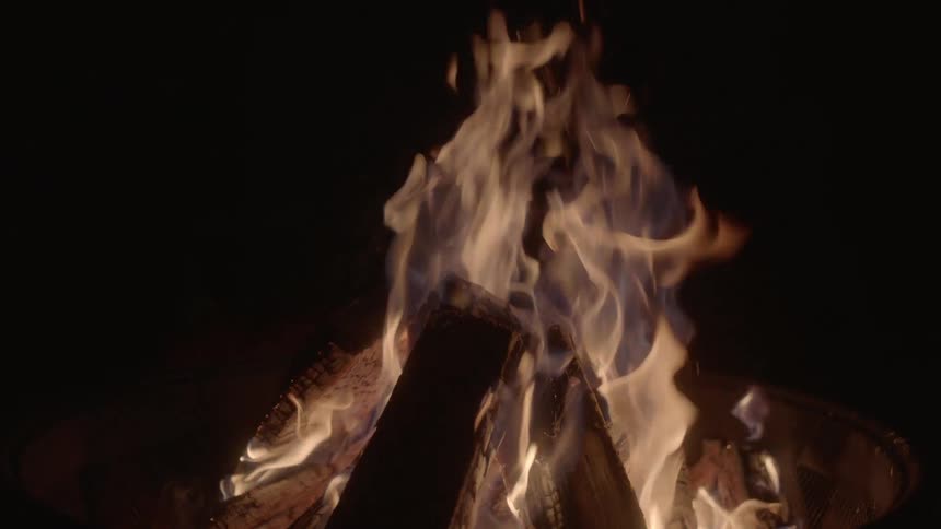 Fire is crackling at night around a campfire