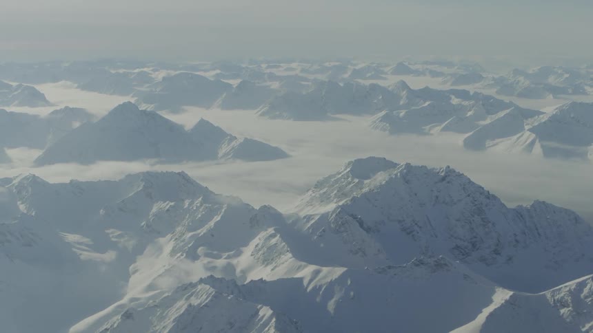 Aerial view of snow covered mountains with fog all over