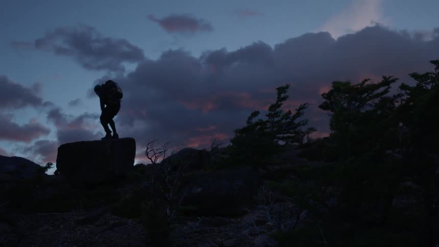 A man climbs on a rock on a windy day